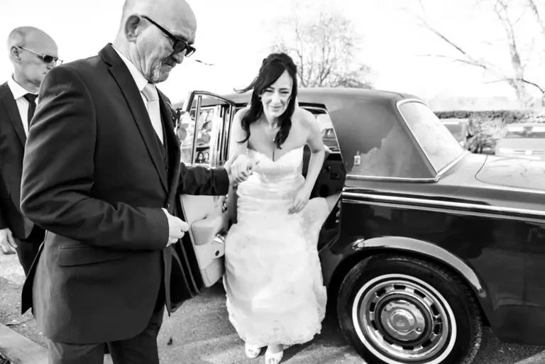 Father of the bride escorting bride arriving in Chauffeur Driven Rolls Royce wedding car